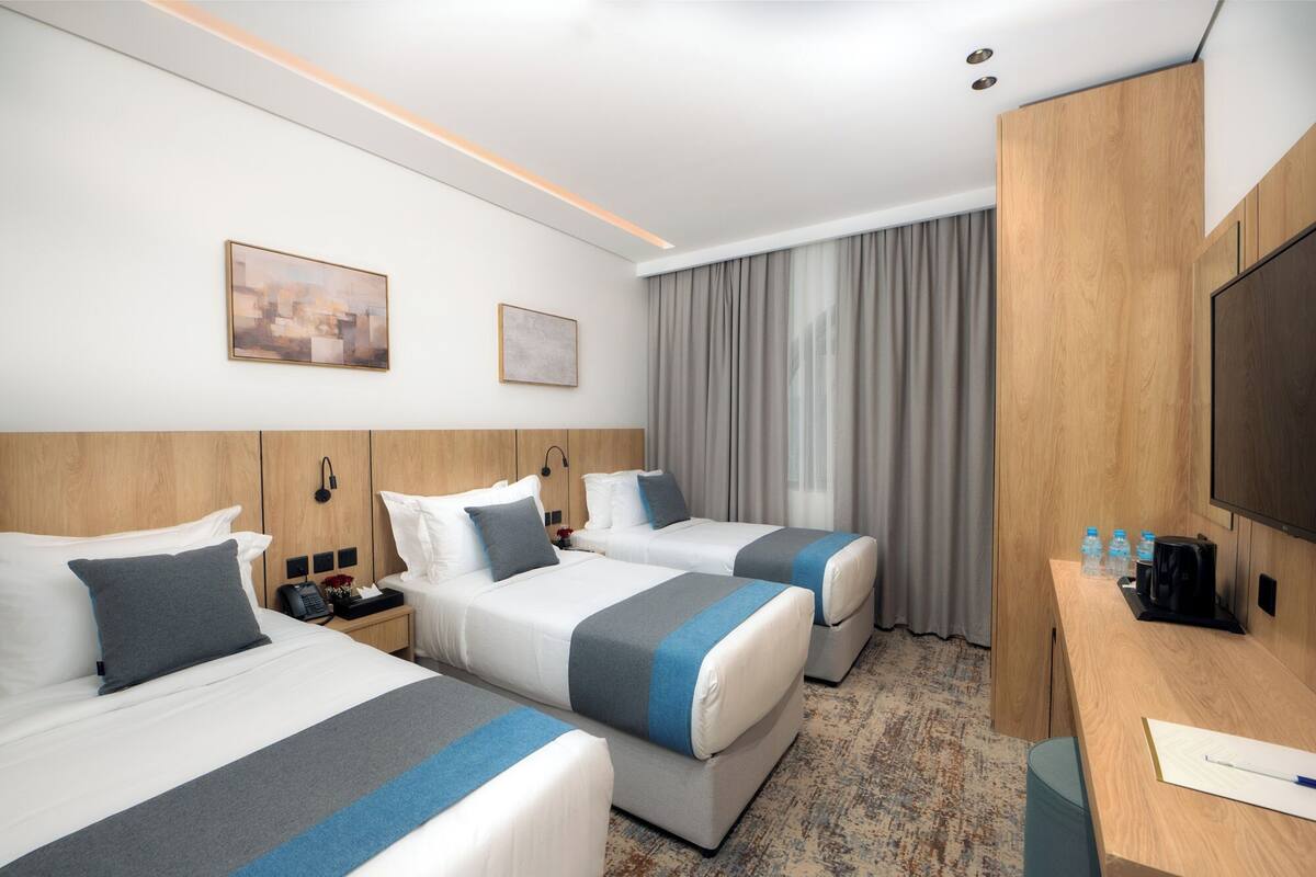Ett hotellrum med två sängar, ett skrivbord och en TV.