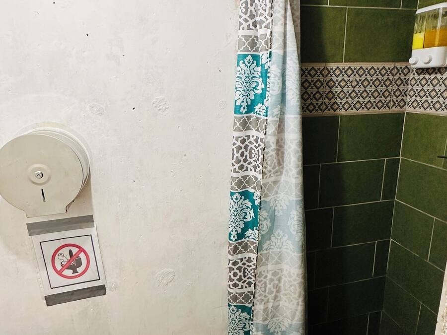 A bathroom with a shower, a toilet, a towel, and a no-smoking sign.