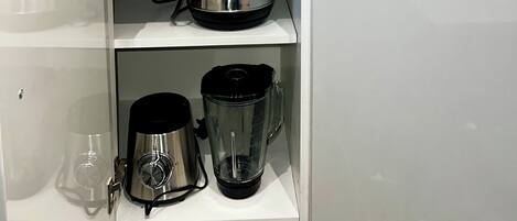 Una cocina con salpicadero de mármol, un hervidor, una cafetera y cajas etiquetadas para azúcar, té y café.