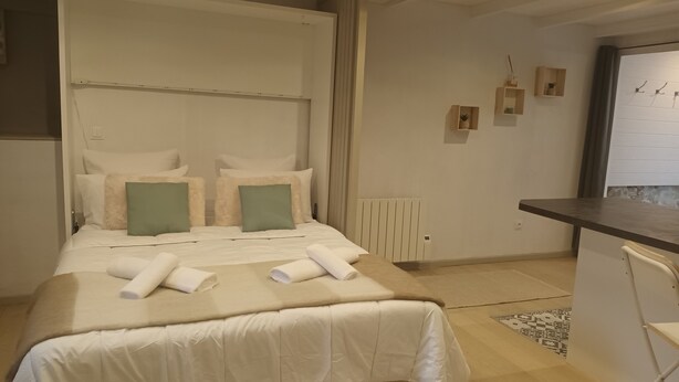A hotel room with a bed, a small desk, and a radiator.