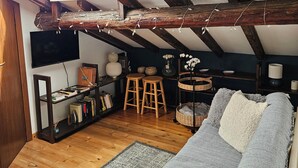 Une pièce de style loft avec des poutres apparentes, un canapé, une petite table et une bibliothèque.