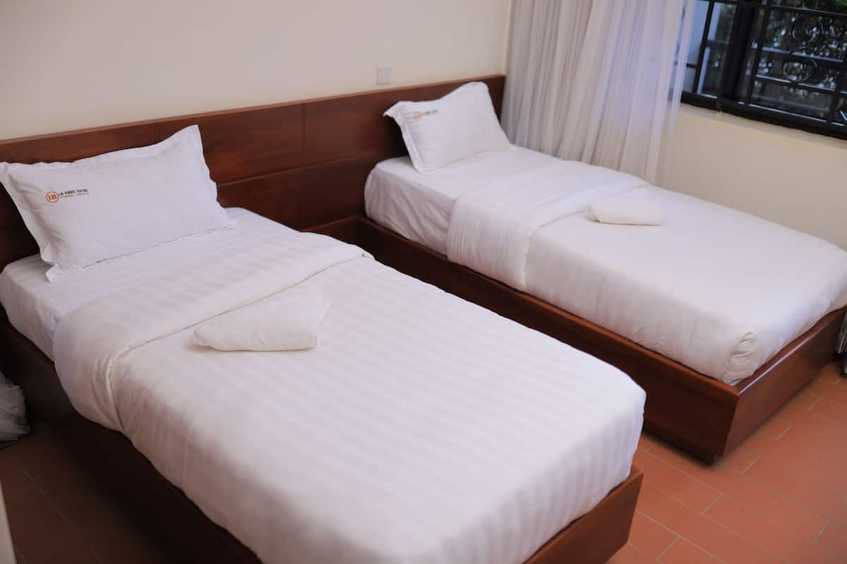 Two single beds with wooden headboards and white bedding in a hotel room.
