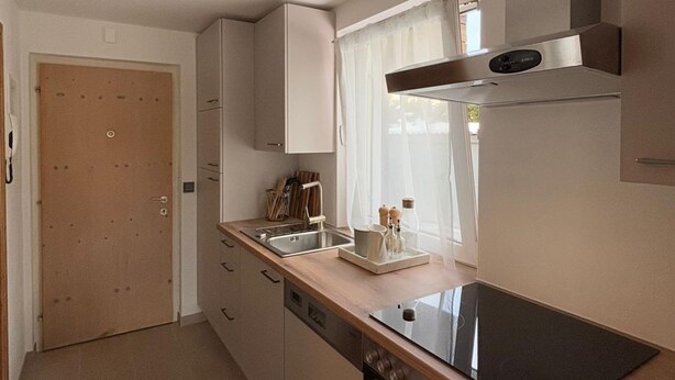 A compact kitchen with a built-in oven, a sink, and a stove. - Apartment in Seefeld Near Ski Slopes (Seefeld in Tirol)