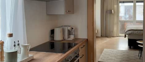 A modern kitchen with a built-in oven, a coffee maker, and a kettle on the counter.