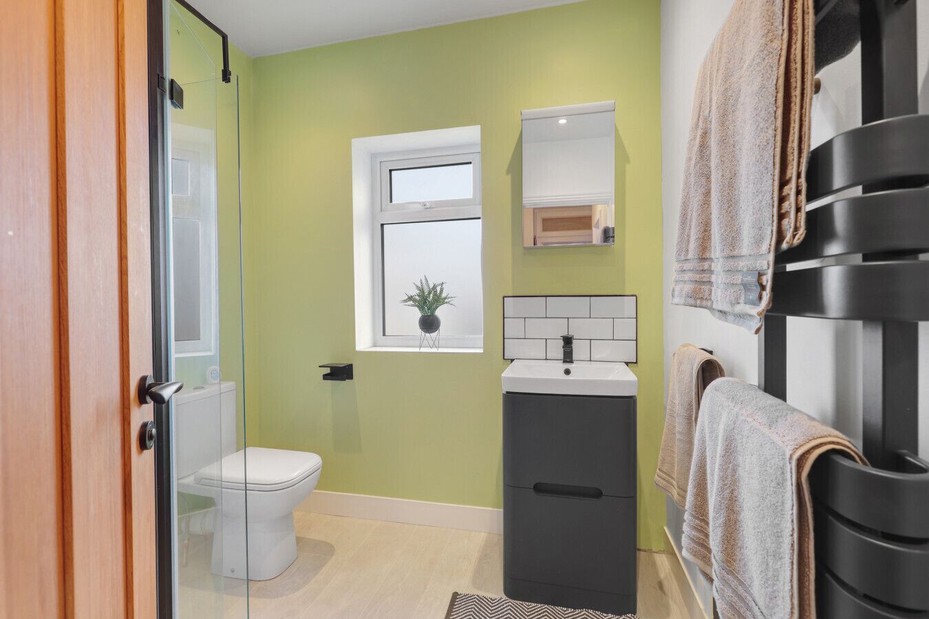Une salle de bain équipée de toilettes, d’un lavabo, d’un miroir et d’un porte-serviettes.