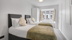 A bedroom with two beds, a window with curtains, and a ceiling light.