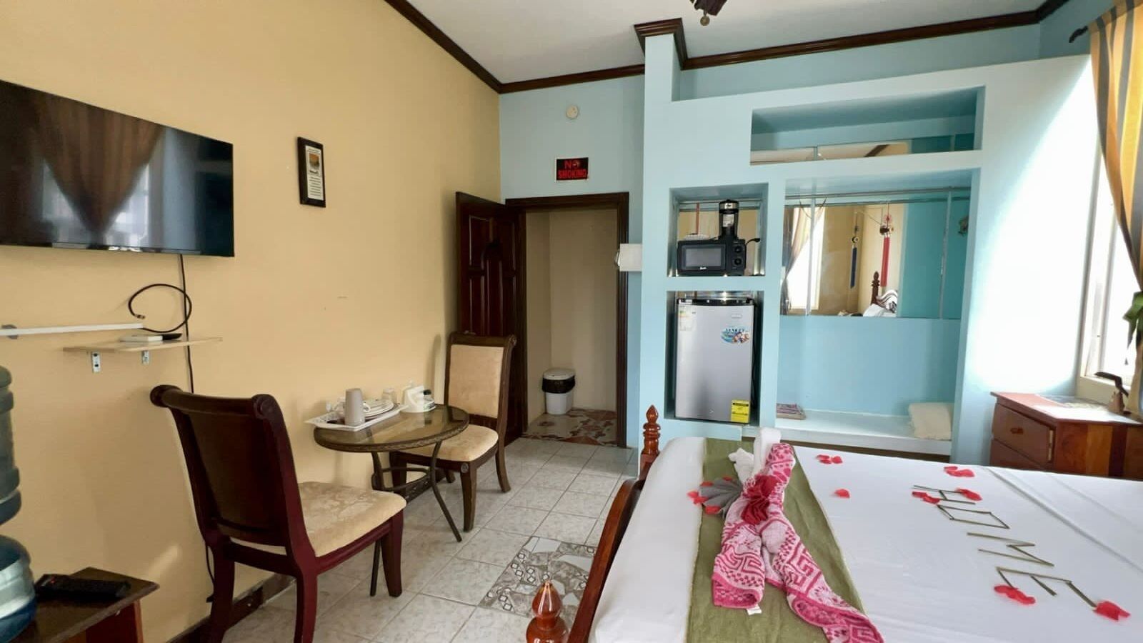 Habitación de hotel con una cama, un escritorio, una silla, un televisor, un microondas y un refrigerador.