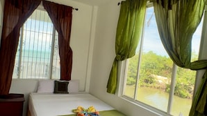 A hotel room with two beds, a view of the outdoors, and a ceiling light fixture.