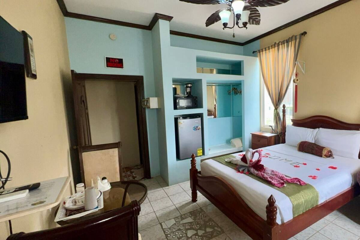 A hotel room with a bed, a desk, a refrigerator, and a television.
