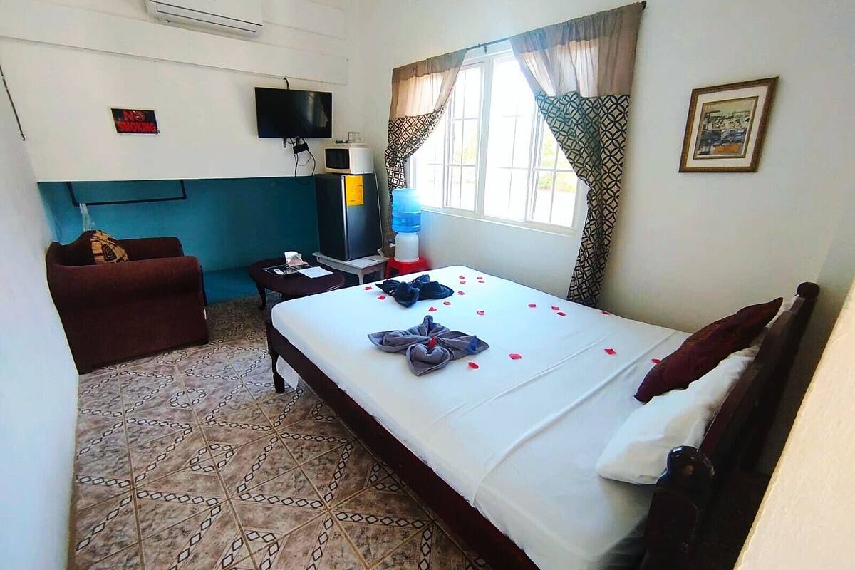 A hotel room with a bed, a TV, a water dispenser, a desk, and a couch.