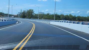 A clear road with a double yellow line, streetlights, and a guardrail.