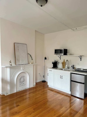 A kitchen with white cabinetry, a microwave, a coffee maker, and a refrigerator.