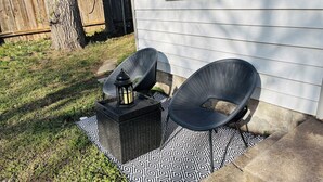 Een terras met twee stoelen, een lantaarn en een kamerkleed met een patroon.