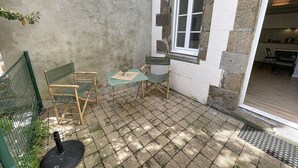 A small patio with a table and chairs, a window, and a door leading to a kitchen. - Charming newly renovated studio with terrace - pets allowed, free Wi-Fi (Granville)