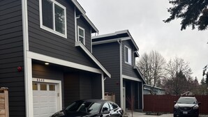 Une maison à deux étages avec un garage, une allée et une voiture garée.
