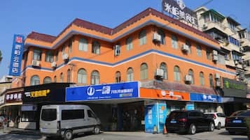 Ein mehrstöckiges Gebäude mit Geschäften im Erdgeschoss, darunter eine Apotheke und ein Servicezentrum.