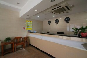 A reception area with a counter, chairs, a wall clock, and a sign. - Homeinn Pebble (Shanghai Qian Tan Shangnan Road Subway Station) (Shanghai)