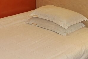 Ein Bett mit weißer, strukturierter Bettdecke und zwei Kissen.