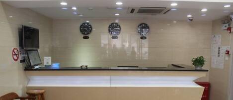 A reception area with a counter, chairs, and clocks on the wall.