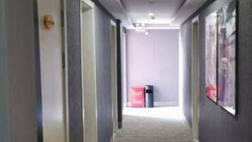 A hallway with doors on both sides, a trash bin, and a poster on the wall.