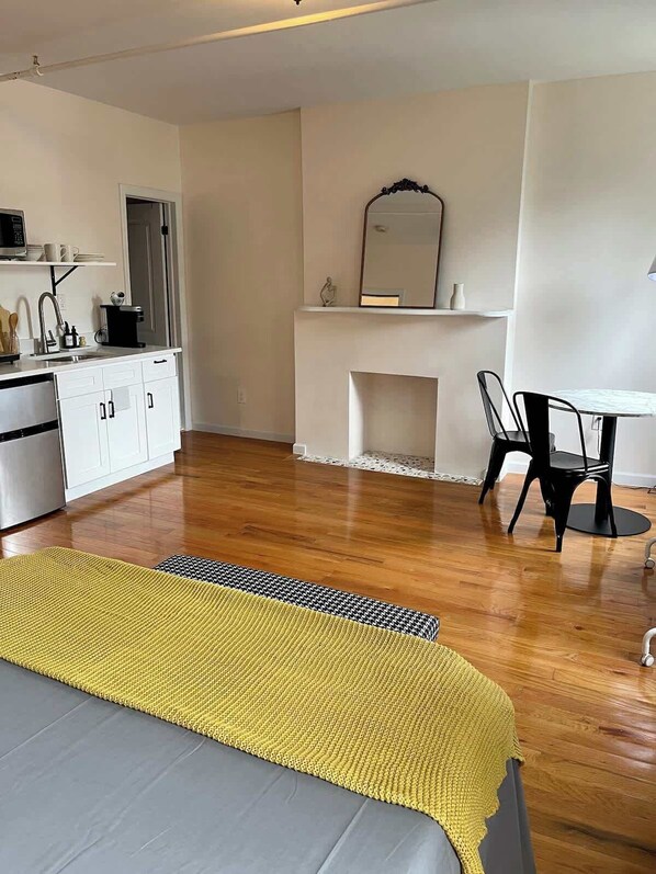 A modern, minimalistic bedroom with a bed, bedside table, and a small desk area.