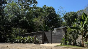 A paved area with a stone wall and a metal fence. - Playa Mantas studio, AC, Parking (Quebrada Ganado)