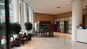 A spacious lobby with a reception desk, seating area, and a bookshelf. - Mingjun Fashion Hotel (Shangqiu)