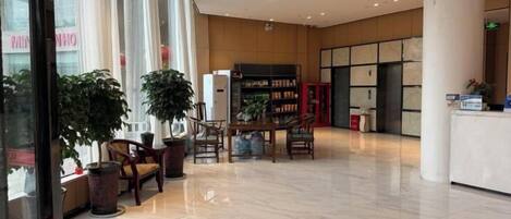 A spacious lobby with a reception desk, seating area, and large windows.