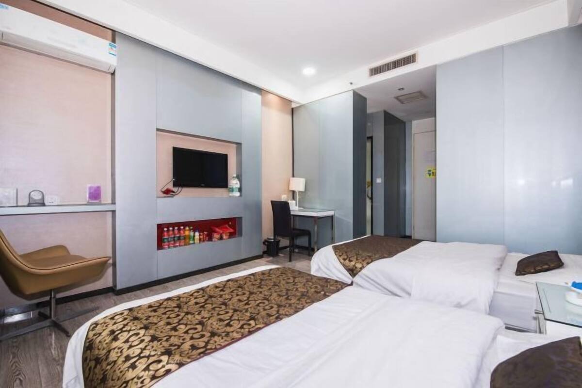 Ein Hotelzimmer mit zwei Betten, einem Schreibtisch, einem Stuhl, einem Fernseher und einer Minibar.