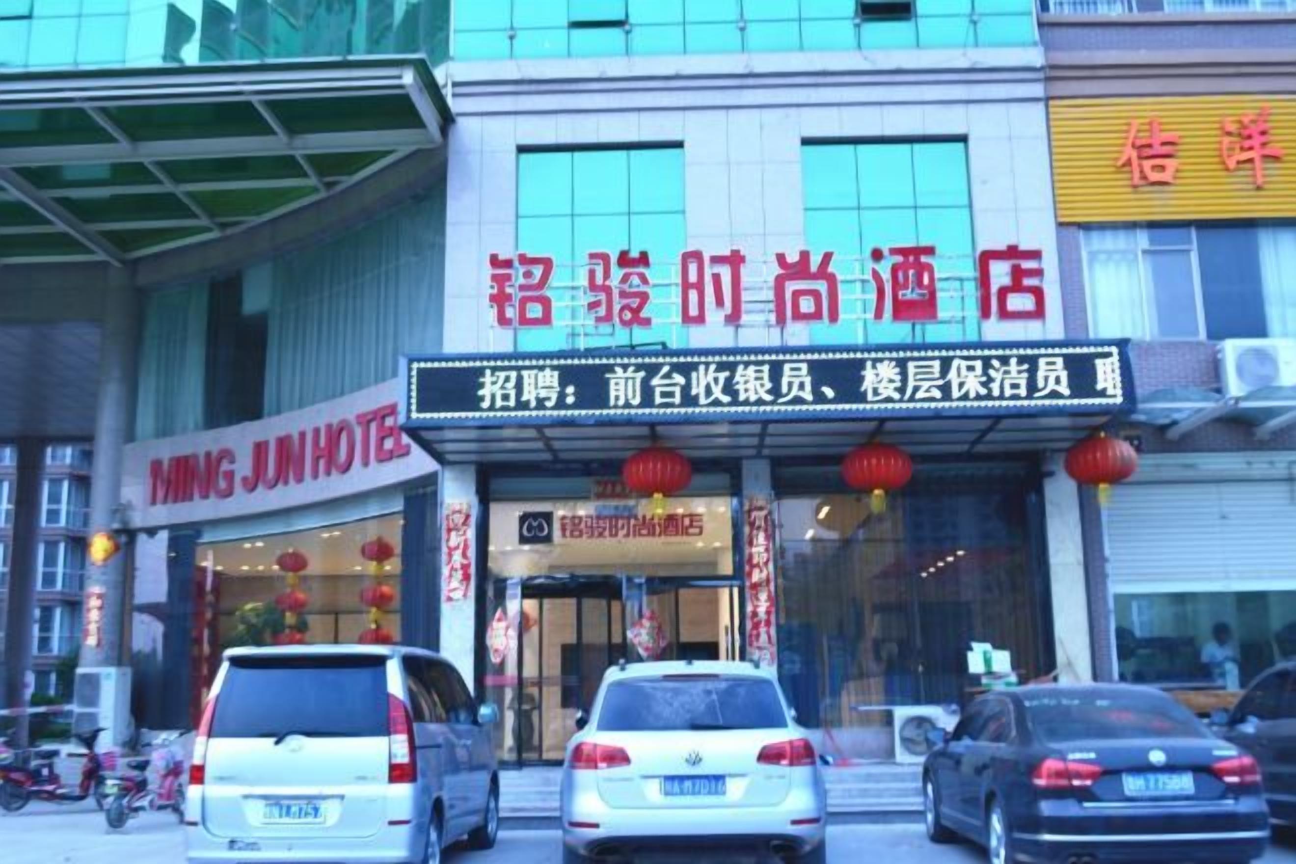 A hotel entrance with a signboard, a car parked in front, and a building facade.