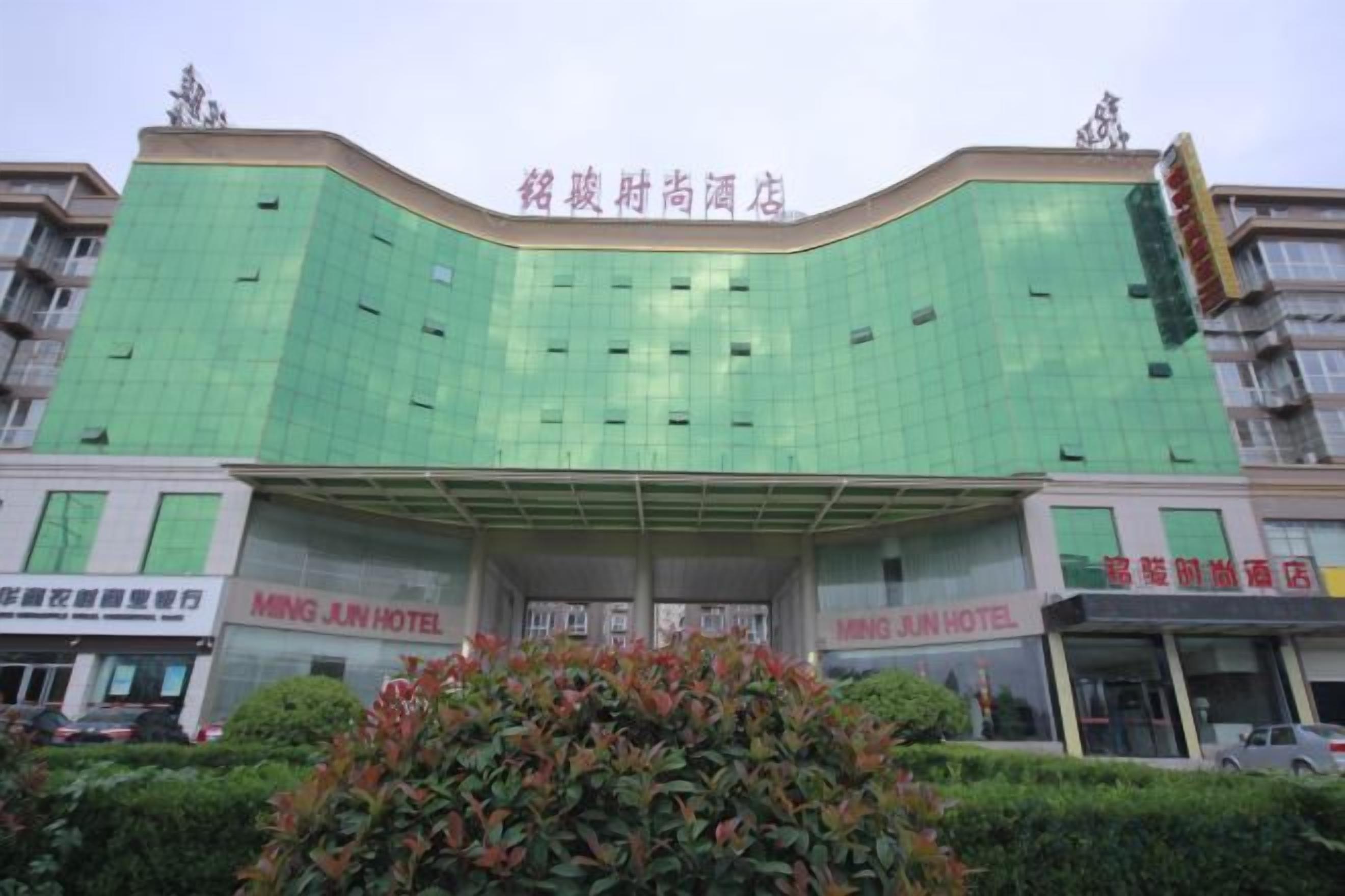 A hotel with a green facade, multiple floors, and signage for the Ming Jun Hotel.