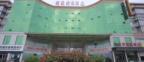 Un hotel con fachada verde, varios pisos y señalización para el Hotel Ming Jun.