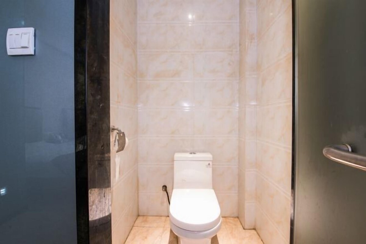 A small, modern bathroom with a toilet, a hand dryer, and a wall-mounted light switch.