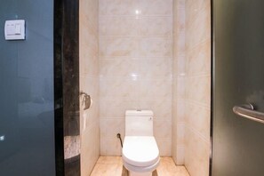 A small, modern bathroom with a toilet, a hand dryer, and a wall-mounted light switch. - Mingjun Fashion Hotel (Shangqiu)