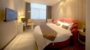 A hotel room with a large bed, a desk with a chair, a television, and a window with curtains. - Mingjun Fashion Hotel (Shangqiu)