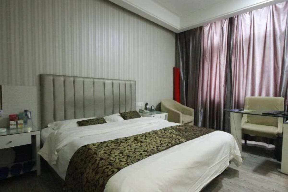 Ein Hotelzimmer mit Bett, Schreibtisch, Stuhl und Nachttisch.