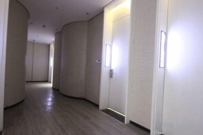 Un corridoio con porte a destra, pavimento in legno e illuminazione incassata.