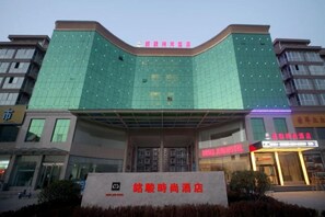 A hotel with a modern facade, a prominent entrance, and signage indicating amenities. - Mingjun Fashion Hotel (Shangqiu)