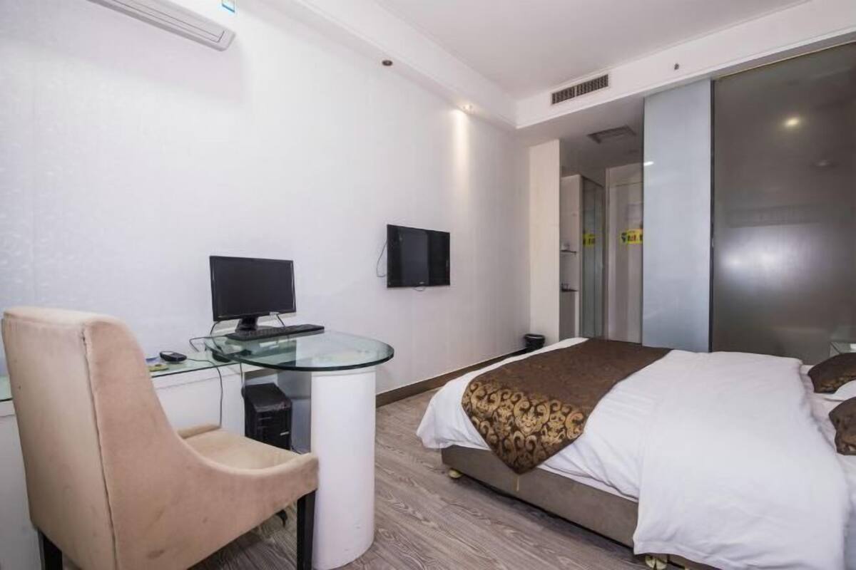 Ein Hotelzimmer mit einem Bett, einem Schreibtisch mit Computer, einem Stuhl und einem Fernseher.