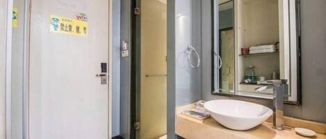 A modern bathroom with a large mirror, a white sink, and a towel rack.