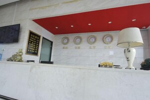 Un área de recepción con mostrador de mármol, techo rojo y un reloj fijado a la pared.