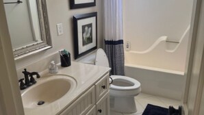 A bathroom with a double sink, toilet, and bathtub. - 5 Bedroom House (Greensboro)