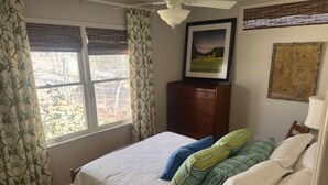 A bedroom with a bed, a dresser, a ceiling fan, and a window with curtains. - 5 Bedroom House (Greensboro)