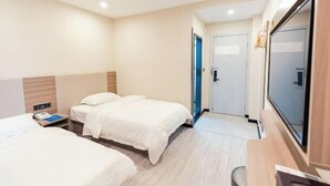 A hotel room with two beds, a desk, a TV, and a door leading to another room. - Jitai Boutique Hotel (Shanghai Expo Park Gaoke West Road Subway Station) (Shanghai)