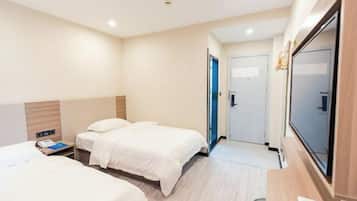 A hotel room with two beds, a desk, a TV, and a door leading to another room.