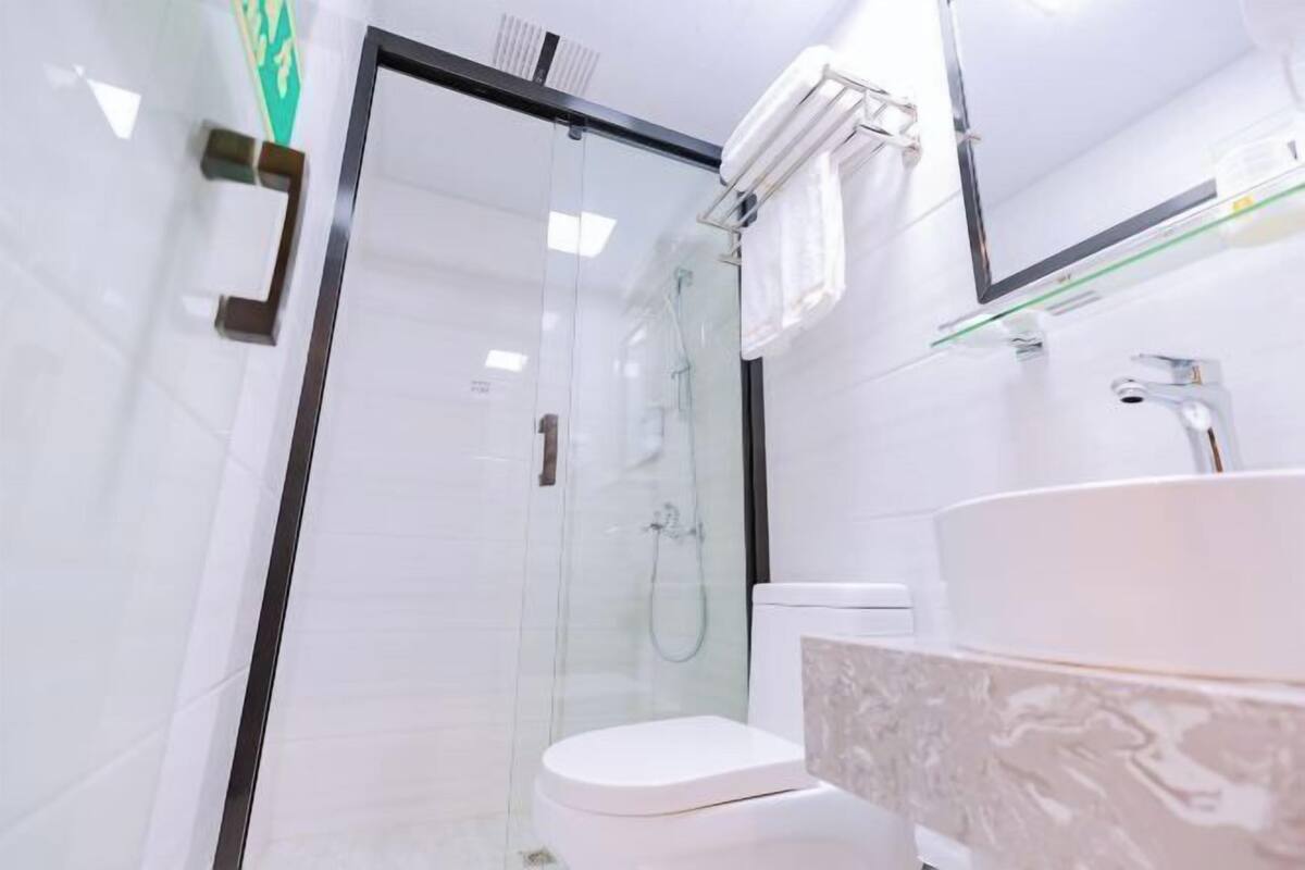 Un baño moderno con ducha de vidrio, inodoro blanco y lavabo color beige.
