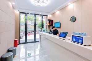 Un área de recepción con mostrador, computadora y pantalla digital.