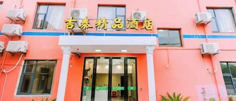 A building with a sign that reads '吉泰药品酒店' and a glass door entrance.