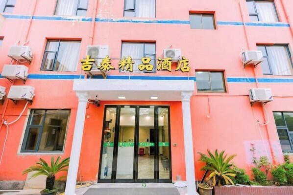 Un edificio con un letrero que dice '吉泰药品酒店' y una entrada con puerta de vidrio.