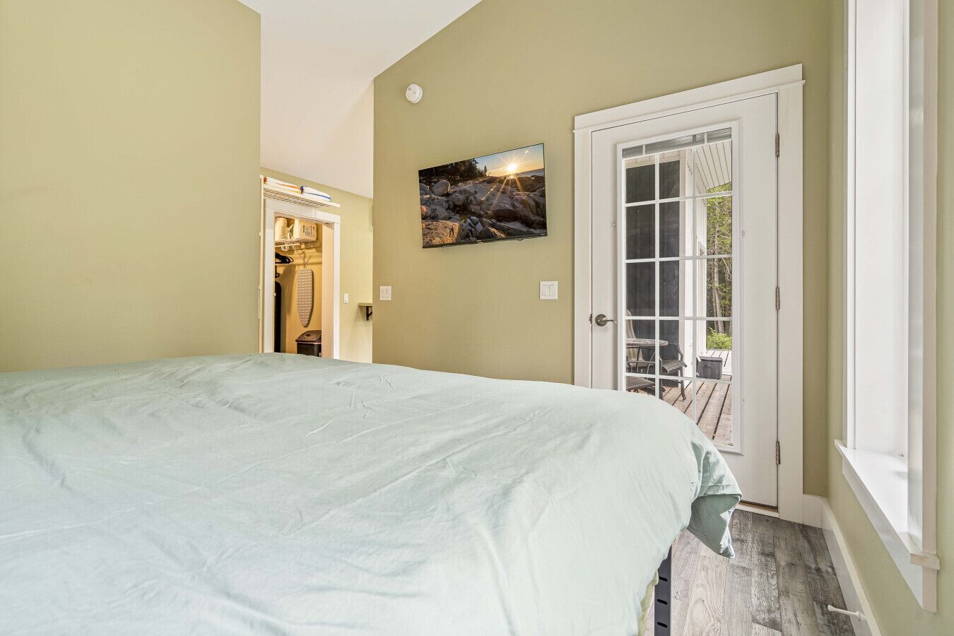 A bedroom with a bed, a door leading to an outdoor area, and a painting on the wall.